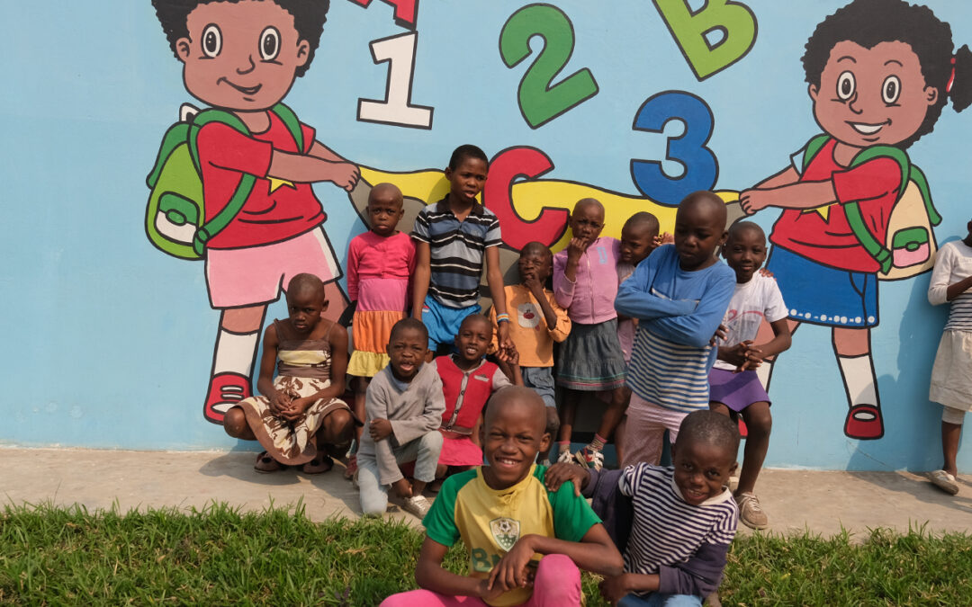Kids in Bana Mayele posing in front of a wall that we painted.